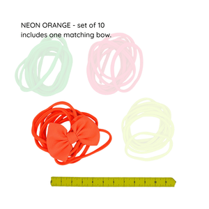 Set of neon orange hair ties with a ruler for size reference on a white background