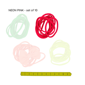 Set of neon pink hair ties with a ruler for size reference on a white background