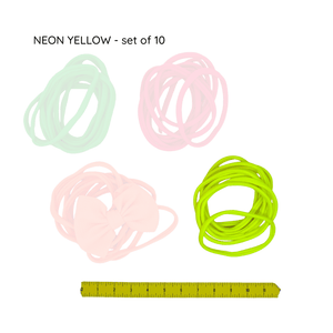 Set of neon yellow hair ties with a ruler for size reference on a white background