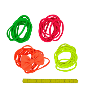 Four bundles of nylon baby headbands in green, pink, orange, and yellow with a ruler for scale on a white background.